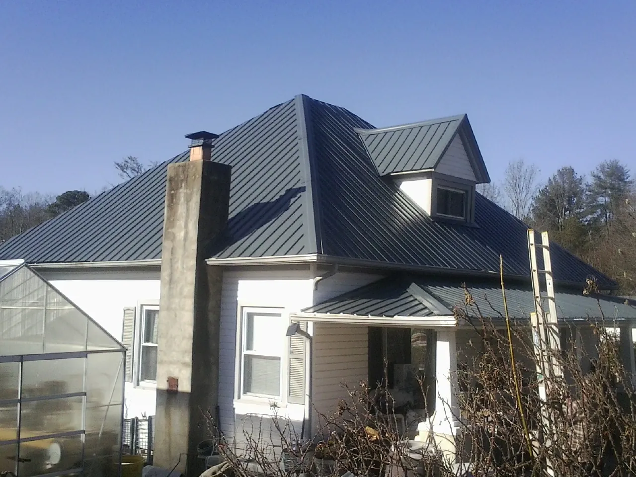 Dark blue standing seam metal roof on a white farmhouse with dormer — Slate & Tile Roof Repair by Roofing Brothers in Linville