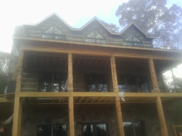 Dormers and porch framing on a large log home under construction — Roof Coating work by our crew in Linville