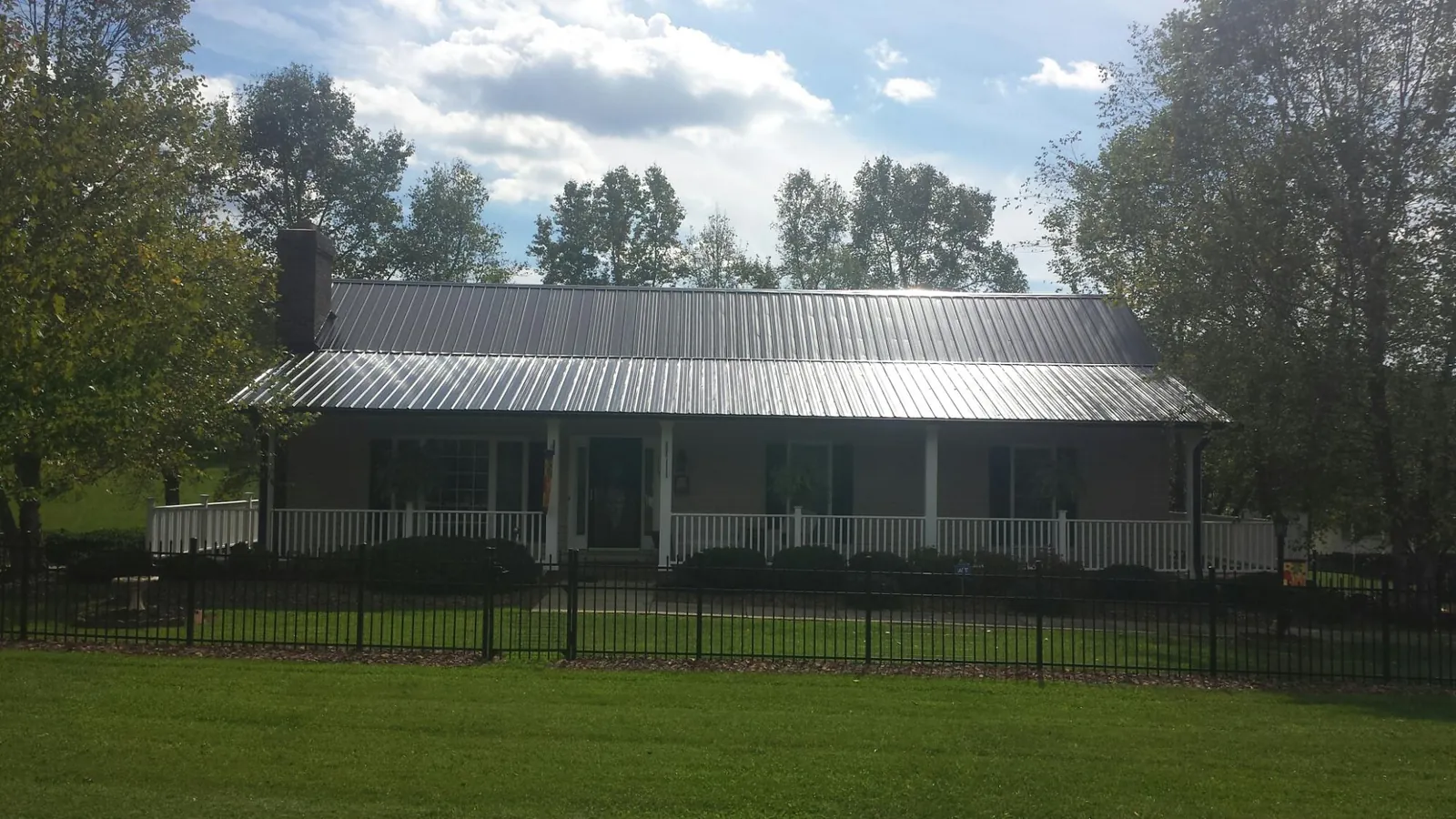 Gray metal roof on a brick ranch with a full width front porch — Gutter Guard Installation work by our crew in Linville