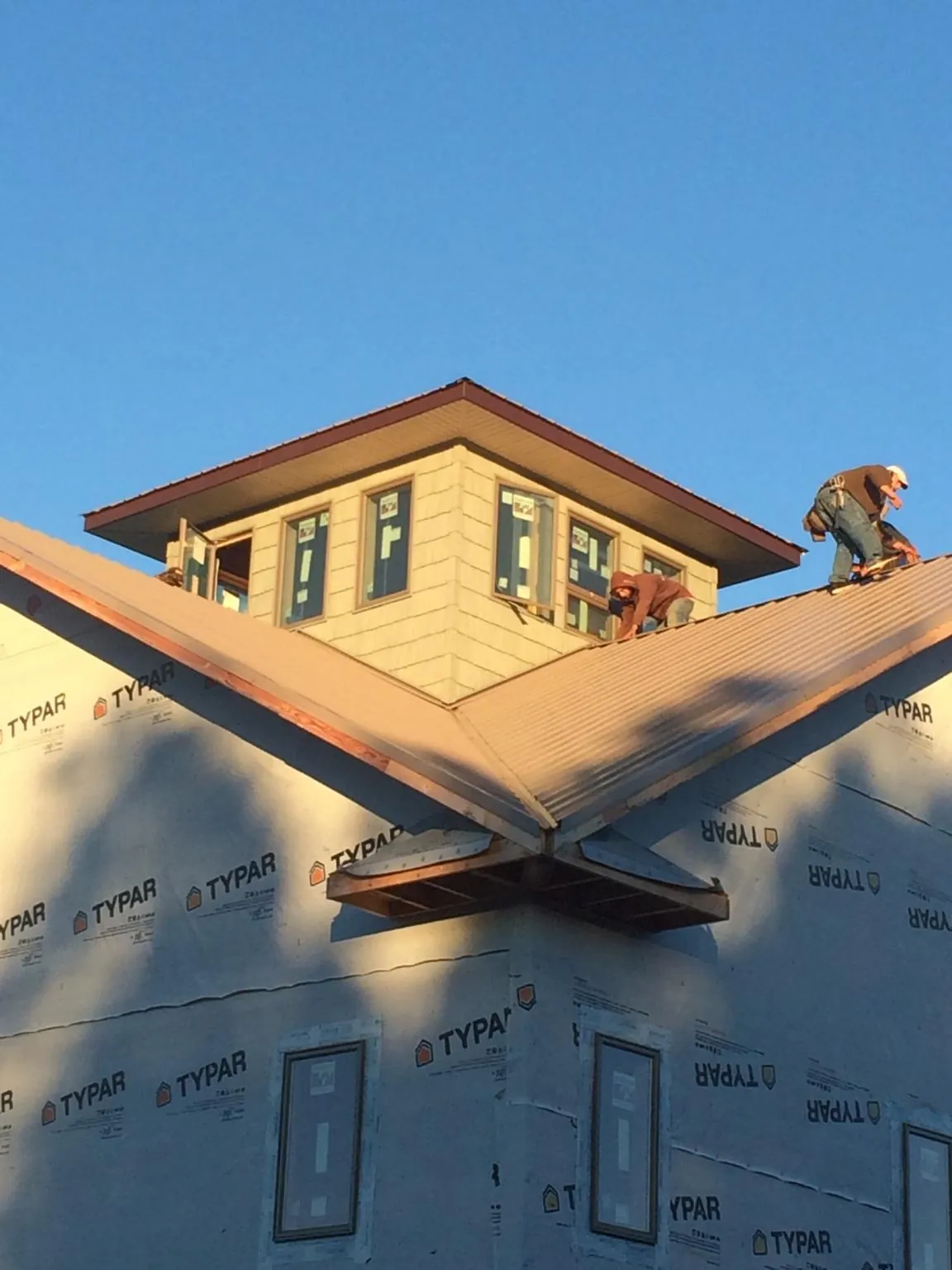 Roofers working around a rooftop cupola on a new metal roof at sunset — Roof Waterproofing in Linville by Roofing Brothers